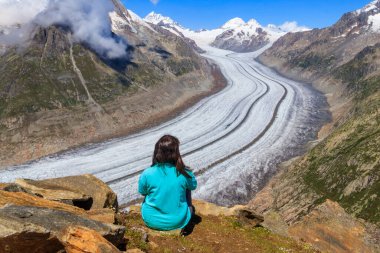 İsviçre Valais Kantonu 'ndaki Büyük Aletsch Buzulu' nun çarpıcı manzarasının tadını çıkaran genç bir kadın.
