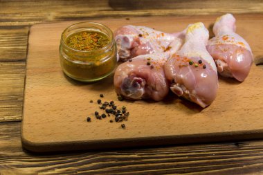Ahşap masa üzerinde kesme tahtası üzerinde baharatlar ile çiğ tavuk budu