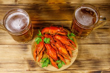 Haşlanmış kerevit ve tahta bir masada iki kupa bira.