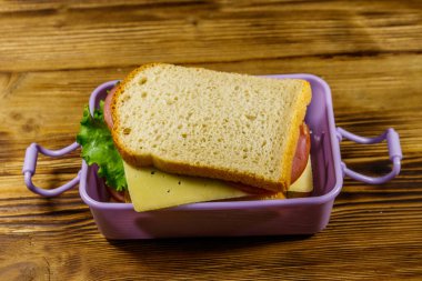 Tahta bir masanın üzerinde sandviç olan beslenme çantası.