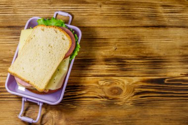 Tahta bir masanın üzerinde sandviçlerle beslenme çantası. Üst görünüm, alanı kopyala