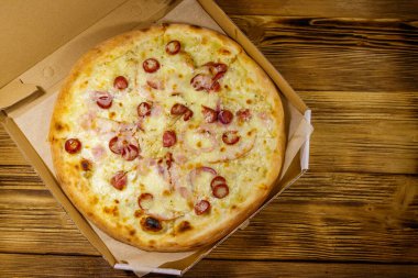 Tahta bir masanın üzerindeki karton kutuda nefis taze pizza. Üst Manzara. Yemek teslimatı, fast food, pizza teslimatı.