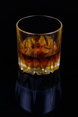 Siyah arka planda bir bardak viski.