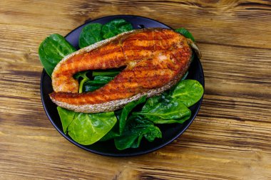 Ahşap masada ıspanaklı ızgara somon bifteği. Üst görünüm