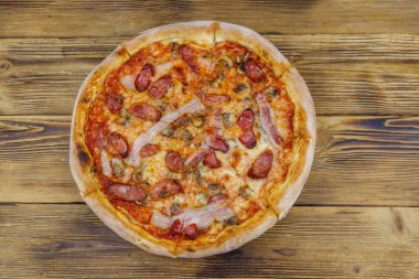Ahşap bir masada sosisli, mantarlı ve peynirli lezzetli taze pizza. Üst görünüm