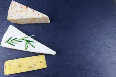 Siyah tahta zemin üzerinde çeşitli peynir türleri. Üst görünüm
