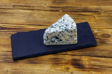 Ahşap masada siyah tahta servis edilen küflü mavi peynir.