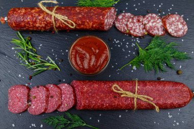 Salamlı sosis, ketçap ve siyah tahtada baharatlar. Üst görünüm