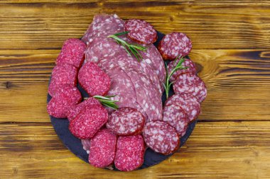 Ahşap masadaki siyah tahtada farklı bir dilimlenmiş salam sosisi. Üst görünüm