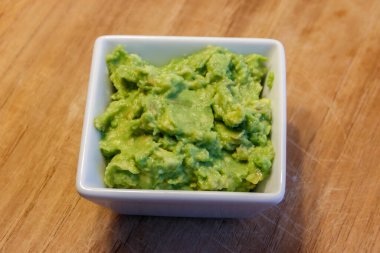 Tahta bir masada bir kase guacamole.