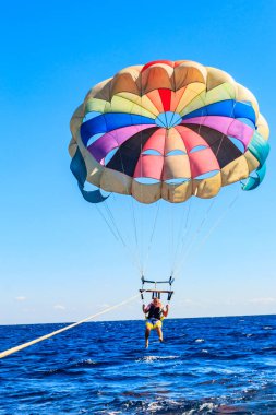 Parasailing su eğlencesi. Deniz kenarında bir yaz tatilinde bir teknenin arkasında paraşütle uçmak. Yaz tatili kavramı