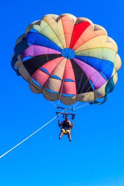 Parasailing su eğlencesi. Deniz kenarında bir yaz tatilinde bir teknenin arkasında paraşütle uçmak. Yaz tatili kavramı