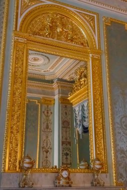 Large mirror in gilded ornate frame on a wall in luxurious room
