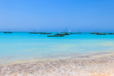 Tropikal kumlu Nungwi plajı ve Tanzanya 'nın Zanzibar kentindeki Hint okyanusundaki geleneksel ahşap dhow tekneleri.