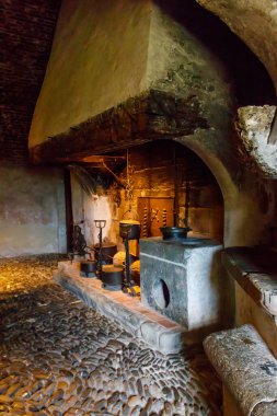 Yemek pişirme aletleri olan bir kalede şömine. Gruyeres kasabasındaki ortaçağ Gruyeres şatosunun içi, İsviçre