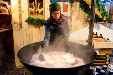 Montreux, İsviçre - 27 Kasım 2022: İsviçre 'nin Montreux kentindeki Noel Pazarı sırasında büyük bir kazanda geleneksel bir Fransız patates, pastırma ve peynir tabağı olan tartiflette pişirme