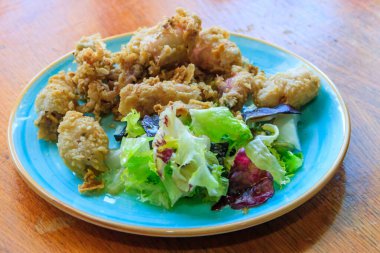 Tahta masada salata ile servis edilen kızarmış yavru ahtapot.