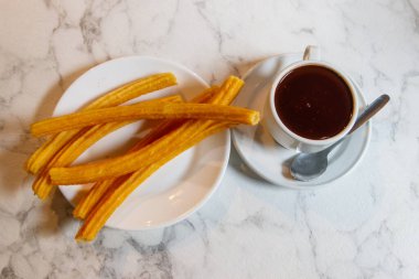 Geleneksel İspanyol tatlısı churros - kızarmış choux pastası ve sıcak çikolata kupası.