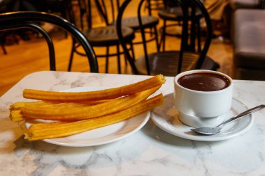 Geleneksel İspanyol tatlısı churros - kızarmış choux pastası ve sıcak çikolata kupası.