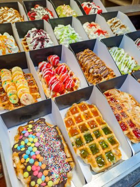 Brüksel, Belçika 'da renkli tatlı soslu Belçika waffleları ve satılık meyveler