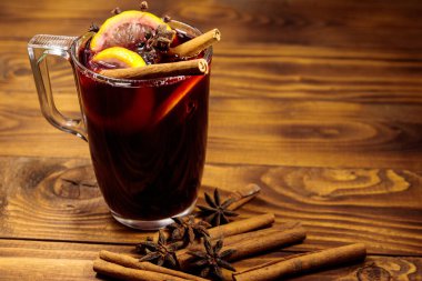 Ahşap masada sıcak şarap ve baharatlar.