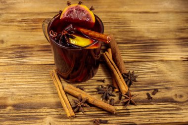 Ahşap masada sıcak şarap ve baharatlar.