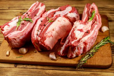 Baharatlı çiğ domuz kaburgası, sarımsak ve ahşap masada biberiye.