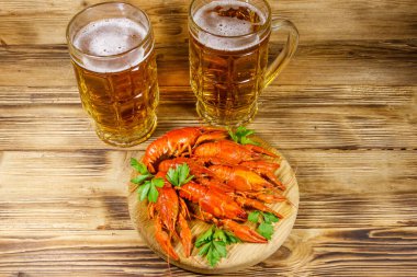Haşlanmış kerevit ve tahta bir masada iki kupa bira.
