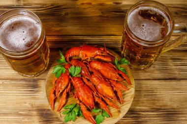 Haşlanmış kerevit ve tahta bir masada iki kupa bira.