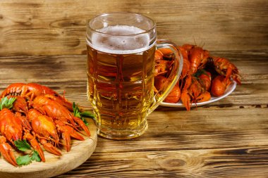 Haşlanmış kerevit ve bir kupa bira ahşap masada.