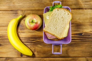 Sandviç, muz ve elmayla dolu bir beslenme çantası. Üst görünüm