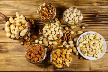 Ahşap masada fındık çeşitleri. Badem, fındık, fıstık, fıstık, ceviz ve küçük kaselerde kaju. Üst Manzara. Sağlıklı yeme kavramı