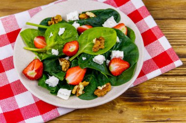 Tahta masada çilekli, ıspanaklı, cevizli ve peynirli taze sağlıklı salata.