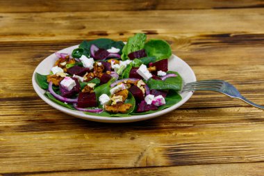 Haşlanmış pancar, peynir, ceviz ve ahşap masada kırmızı soğanlı ıspanak salatası. Sağlıklı vejetaryen yemekleri