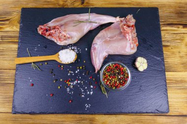 Çiğ tavşan bacağı ve üzerinde baharat olan tahta tahta tahta kesme tahtası. Üst görünüm