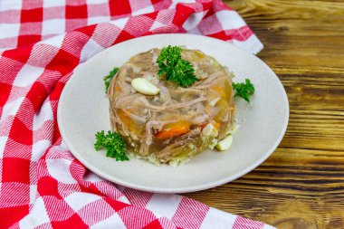 Meat aspic in a plate on a wooden table. Traditional russian dish clipart