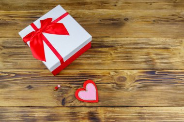 Ahşap bir arka planda hediye kutusu ve kırmızı kalp. Sevgililer Günü konsepti