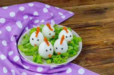 Ahşap masada haşlanmış yumurtalarla komik bir Paskalya kahvaltısı.