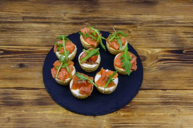 Somonlu turta, krem peynir ve ahşap masada roka.