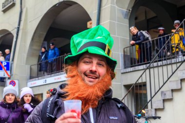 Bern, İsviçre - 25 Şubat 2023: İsviçre, Bern 'deki karnaval sırasında yeşil cüce şapkalı bir adamın portresi