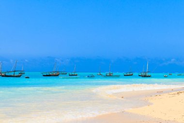 Tropikal kumlu Nungwi plajı ve Tanzanya 'nın Zanzibar kentindeki Hint okyanusundaki geleneksel ahşap dhow tekneleri.