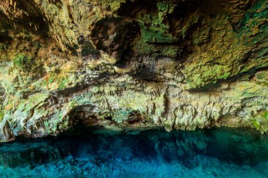 Kayalık bir mağarada dikitler ve dikitlerle oluşmuş güzel bir kristal berrak su havuzu manzarası. Tanzanya, Zanzibar 'daki Kuza mağarası