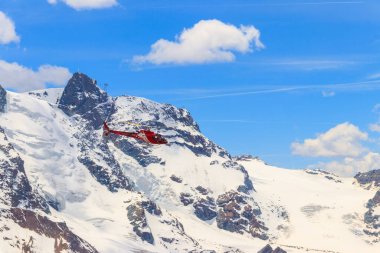 İsviçre 'deki karlı İsviçre Alpleri üzerinde uçan helikopter.