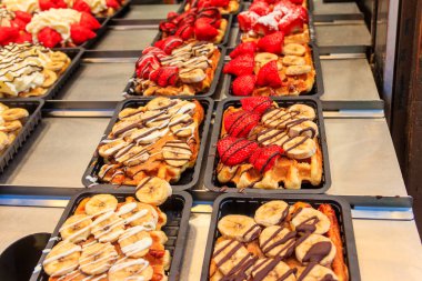 Brüksel, Belçika 'da renkli tatlı soslu Belçika waffleları ve satılık meyveler