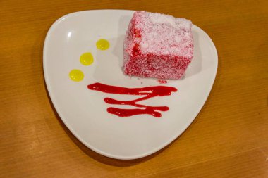 Tahta masanın üzerinde bir parça pembe pasta.