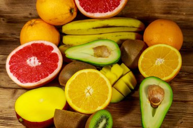 Ahşap masa üzerinde tropikal meyve çeşitleri. Muz, mango, portakal, avokado, greyfurt ve kivi ile natürmort