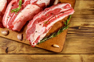 Ahşap masada baharat, sarımsak ve biberiye ile çiğ domuz kaburga. Üstte görüntü