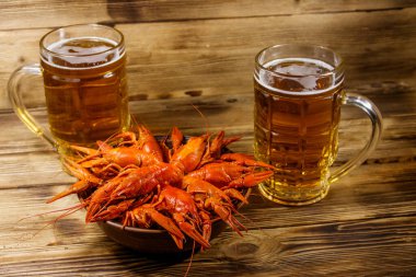 Haşlanmış kerevit ve tahta bir masada iki kupa bira.