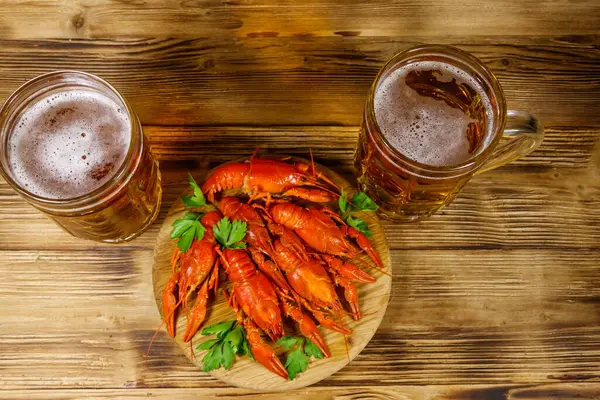 Haşlanmış kerevit ve tahta bir masada iki kupa bira.