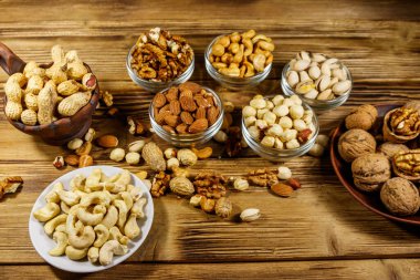 Ahşap masada fındık çeşitleri. Badem, fındık, fıstık, fıstık, ceviz ve küçük kaselerde kaju. Sağlıklı yeme kavramı